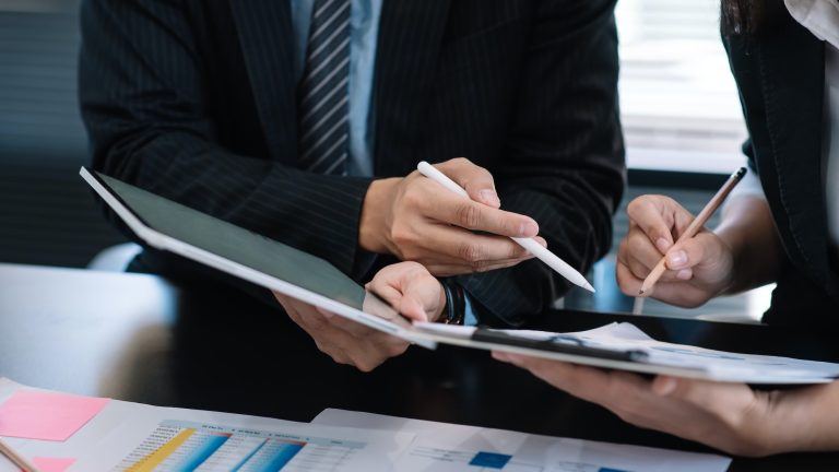 Image of a businessman meeting at the office with a tablet pointing to a graph.